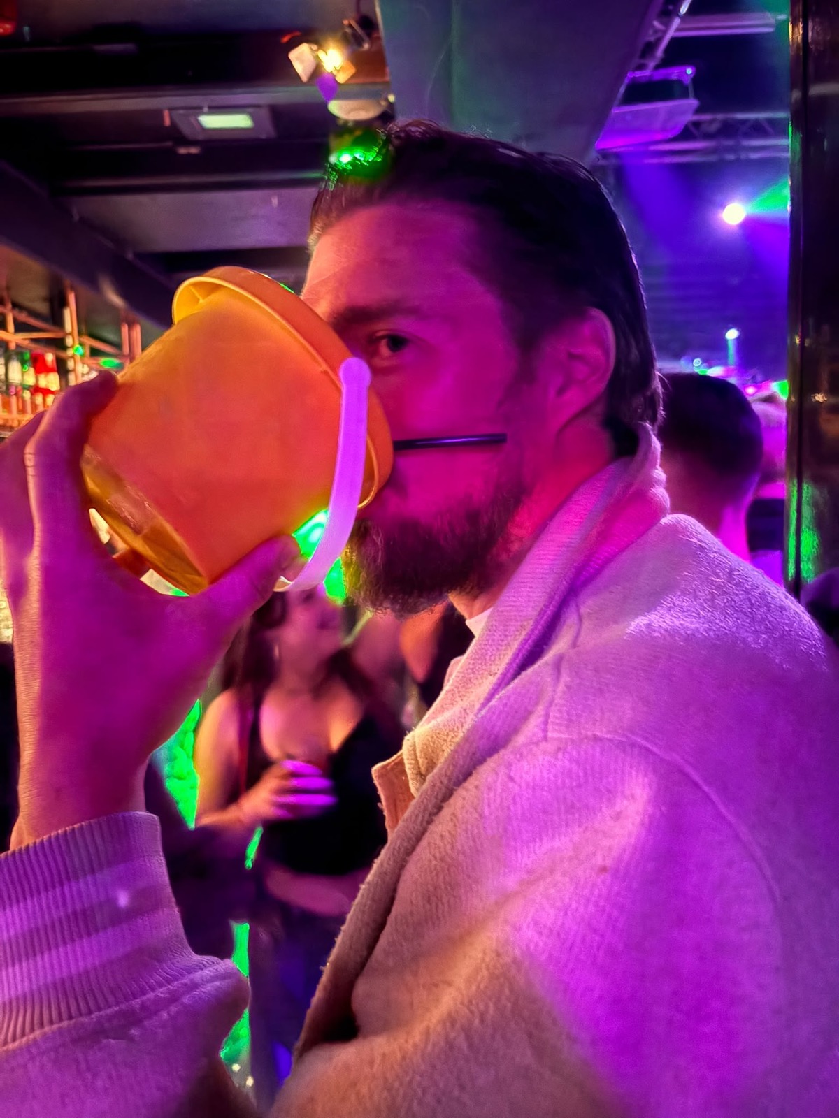 Derks drinkt in de kroeg bier uit een oranje emmertje met een rietje